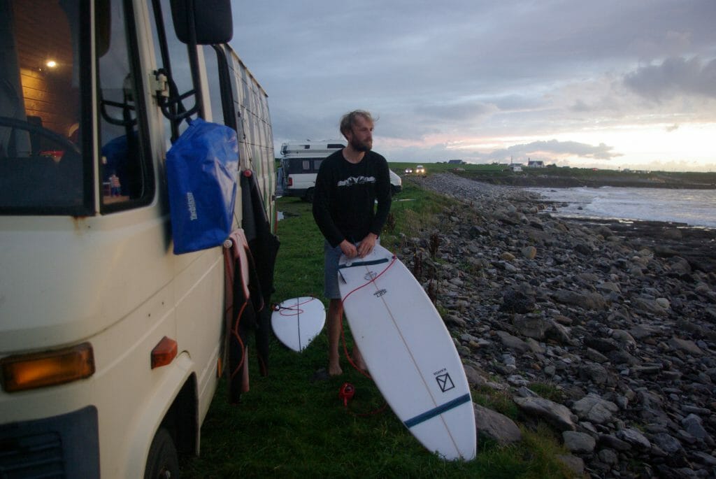 Kanoa Surfboard im Test: Der Blogger Luca Brück schraubt di Finnen ins Board und blickt dabei aufs Meer