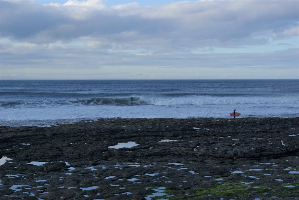 Surfen in Irland: Ein Surfer mit orangenem Surfbrett am Strand von Easkey