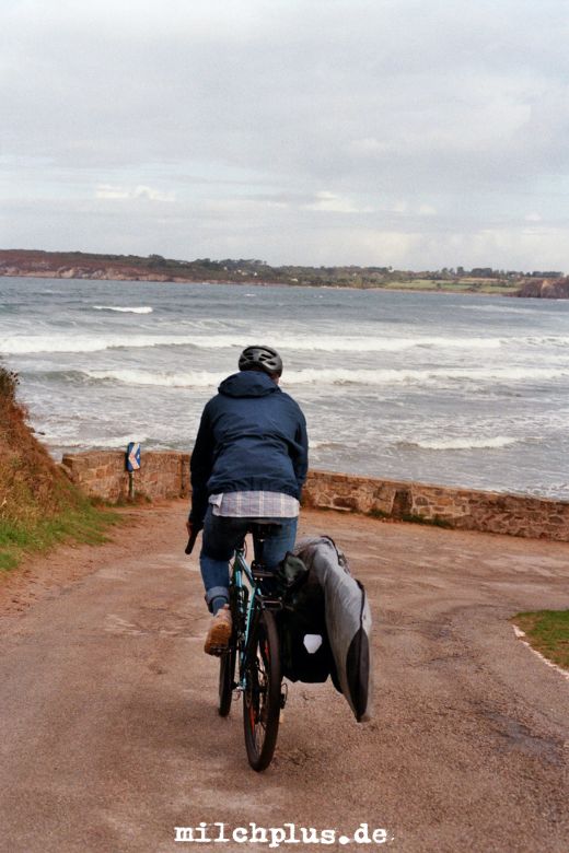 Surfen in der Bretagne: Ein Surfer auf dem Fahrrad mit einem Surfbretthalter und Gepäck