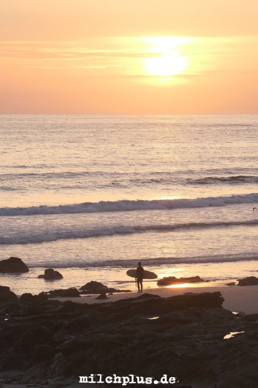 Eine Surferin blickt in den Sonnenuntergang