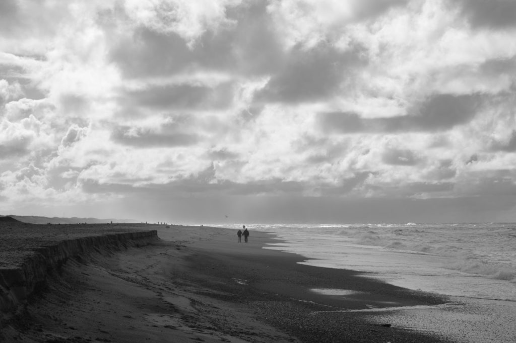 Roadtrip durch Dänemark: Zwei Menschen gehen Hand in Hand am Strand spazieren