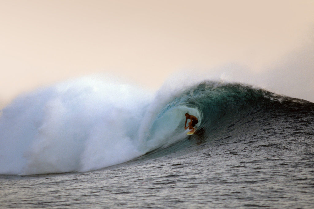 Surfen in Indien: Ein Surfer surft eine Welle im Abendlicht.