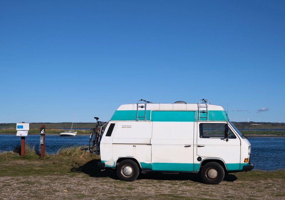 Camper mieten in Deutschland: Titelbild. Ein VW T3 steht in Dänemark vor einem See mit einem trocken gefallenen Segelboot.