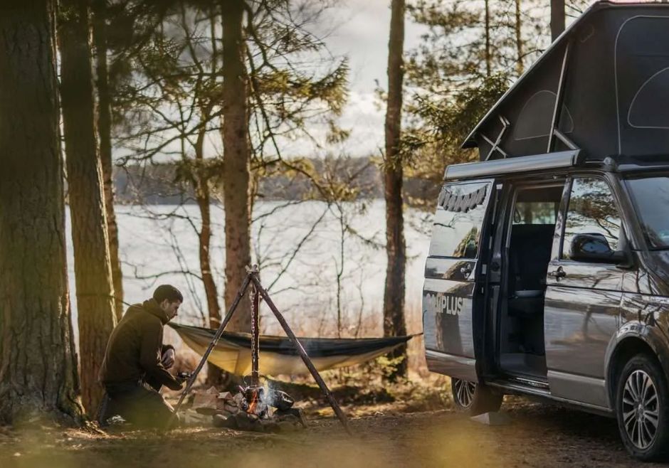 Camplust im Test: Titelbild, ein Mann macht ein Feuer neben einem Campingbus