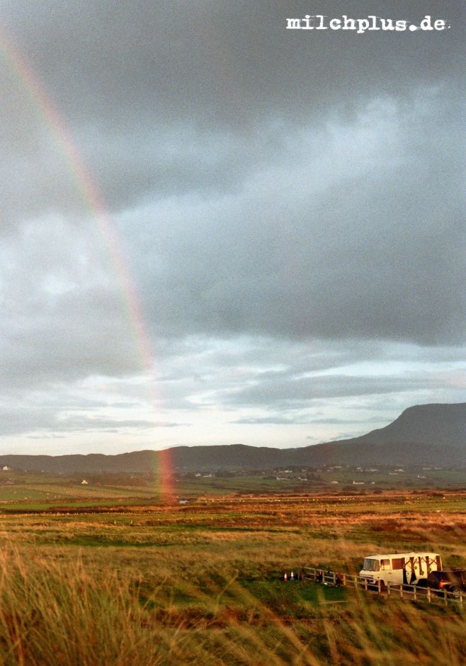 Ein Regenbogen endet nur wenige hundert Meter hinter einem Camper