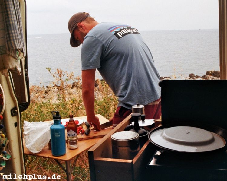 VW Bus Camper: Ein Mann kocht vor dem T3 vor dem Meer